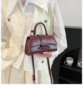 Detail of wine red hourglass handbag with retro oil wax texture and circular ring buckle