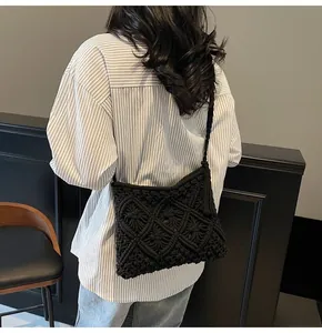 Detail view of black macrame crossbody bag with diamond patterns and fringe on a model