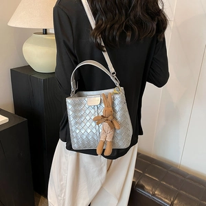Silver woven bucket bag with rabbit charm and adjustable strap shown on model