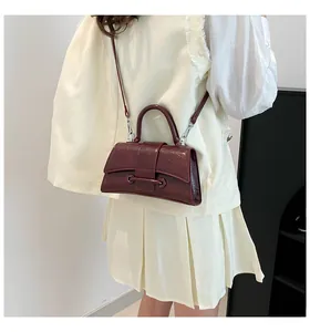 Detailed view of dark red hourglass bag with leather texture and unique curved flap design