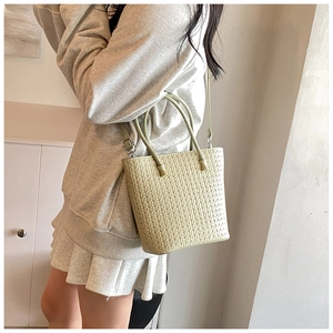 Detail showing the woven texture of the light green minimalist shoulder bag in daily use