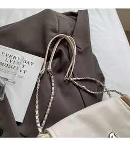 Détail d'un sac à rabat en cuir beige avec bandoulière chaîne et fermoir métallique