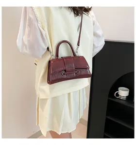 Detail shot of a burgundy vintage handbag with polished hardware and hard top handle