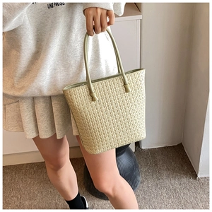 Detailed texture of light green hand-woven tote bag with elegant thin handles