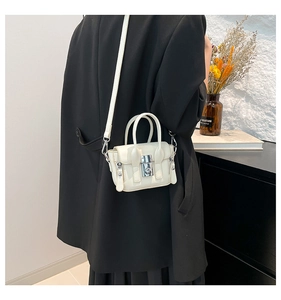 Mini sac bandoulière crème avec boucle argentée porté par un modèle en veste noire chic