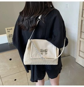 Détail du sac bandoulière en paille tissée avec boucle nœud argenté et chaîne