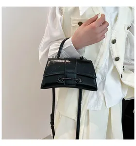 Detail view of black wrinkled shiny leather handbag with adjustable shoulder strap