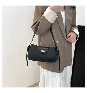 Detail of black pebbled leather shoulder bag with silver metal twist lock on model