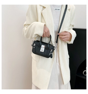 Détail d'un mini sac messager noir avec fermoir argenté et glands décoratifs