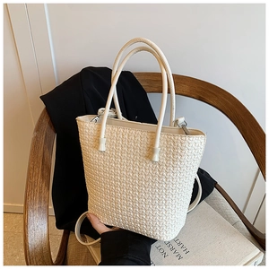 Detail of off-white woven texture tote bag with top handle and slender shoulder strap