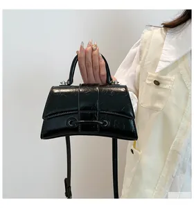 Detail of black croc-effect hourglass handbag with glossy leather finish and top handle