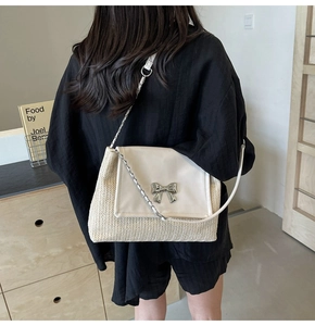 Détail du sac en paille tissée avec rabat en cuir beige et boucle de nœud argentée