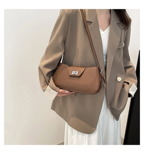 Detail view of a brown pebbled leather shoulder bag with a silver twist lock on model