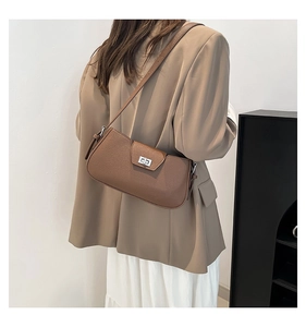 Detail of brown leather shoulder bag with lychee texture and silver twist lock closure