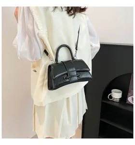 Detail of a vintage black hourglass crossbody bag with adjustable strap in home setting
