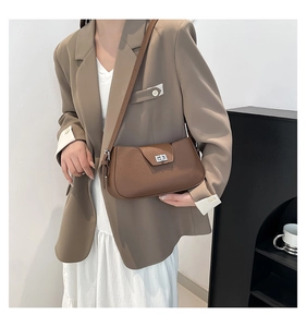 Detail of a brown lychee pattern leather shoulder bag featuring a silver metal turn-lock