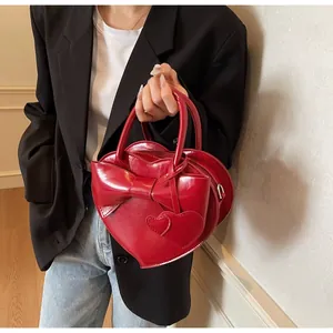 Macro detail of red heart-shaped leather handbag with bow decoration and glossy finish