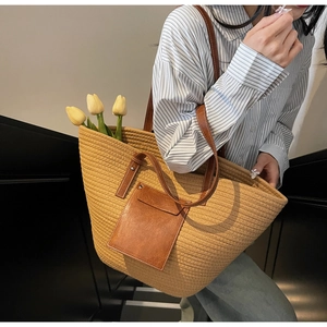 Detail of hand-woven tote bag with brown leather side pocket and long shoulder strap