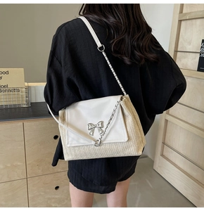 Détail du sac à bandoulière en paille tissée avec rabat en cuir blanc et nœud argent