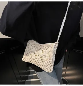 Close-up of white macrame bucket bag with geometric knit patterns and fringe detail