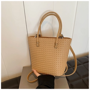 Detail of woven texture tote bag with round handles and adjustable strap in beige