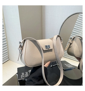 Detail of beige lychee grain leather bag with silver rectangular turn-lock closure