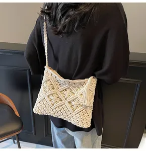 Macro detail of cream macrame knit bucket bag with long side tassels and woven shoulder strap