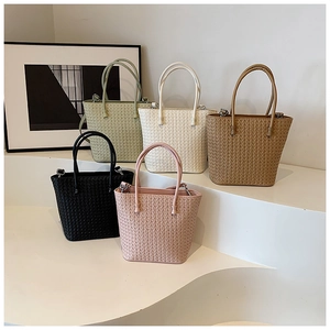 Collection of woven tote bags in five colors displayed on white minimalist steps