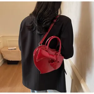 Detail of red heart-shaped shoulder bag in patent leather with a large decorative bow