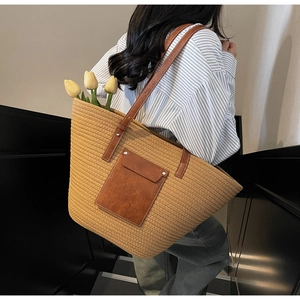 Detail of woven tote bag with brown leather pocket and long straps on stairs