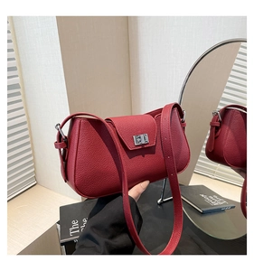 Detail of dark red lychee grain leather handbag featuring a silver square metal twist lock