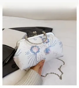 Detail of vintage floral embroidery and engraved silver metal frame on a cream handbag