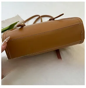 Dettaglio della base della borsa in pelle marrone con cuciture precise e forma cilindrica