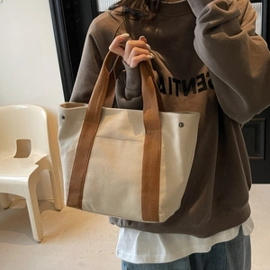 Minimalist beige canvas tote bag with brown handles and sturdy metal rivets for daily use