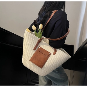 Detail of woven tote bag with brown leather straps and front pocket showing texture