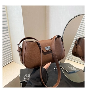 Detailed view of brown litchi grain leather texture and silver rotating metal lock