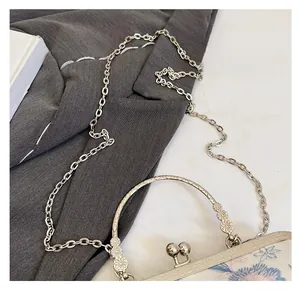 Detail of vintage floral fabric handbag featuring a carved metal handle and silver chain