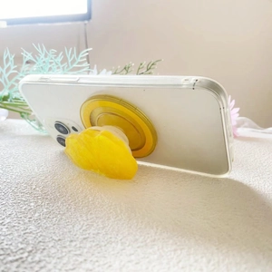 Détail du support de téléphone en acrylique irisé jaune montrant la texture cristalline