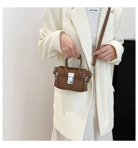 Détail d'un mini sac carré en cuir marron avec boucle en métal argenté et bandoulière
