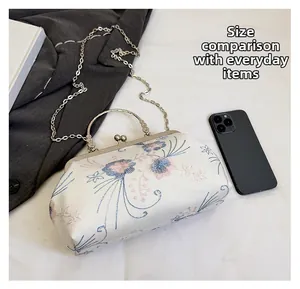 Floral embroidery satin clutch bag shown with smartphone for size scale comparison