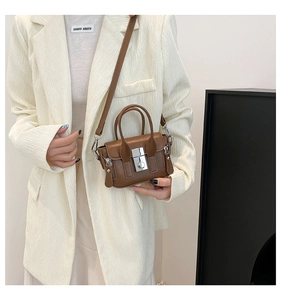 Détail d'un mini sac carré marron avec fermoir métallique argenté et coutures verticales