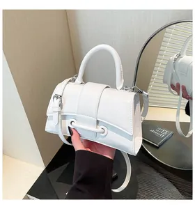 Close-up of a white leather hourglass handbag with single handle and crossbody strap detail