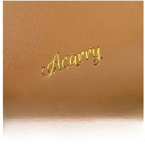 Dettaglio macro del logo dorato Acarry sulla trama in pelle marrone caramello pregiata