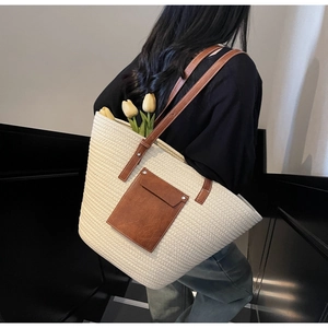 Close-up of beige woven tote bag with brown leather pocket and adjustable shoulder strap