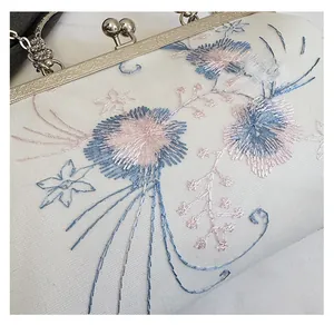 Detailed view of floral embroidery and vintage silver metal clasp on white fabric bag