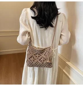 Detail of hand-woven beige knit bucket bag with bohemian tassel and diamond pattern