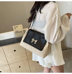 Détail d'un sac bandoulière en paille et cuir noir avec nœud argenté sur une personne