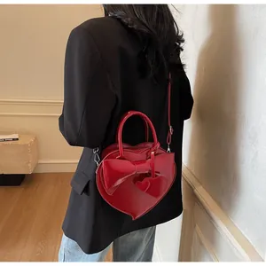 Detail of red heart-shaped bag featuring a 3D bow and dual-heart pendant charms