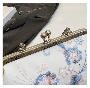 Detailed macro shot of vintage golden carved clasp and floral embroidery on a retro handbag