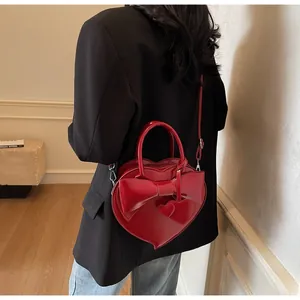 Detailed view of a heart-shaped red patent leather bag with bow on black blazer